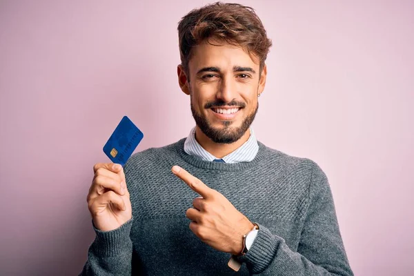 若いです顧客男とともに髭保持クレジットカードのために支払い上のピンクの背景非常に幸せなポインティングとともに手と指 — ストック写真