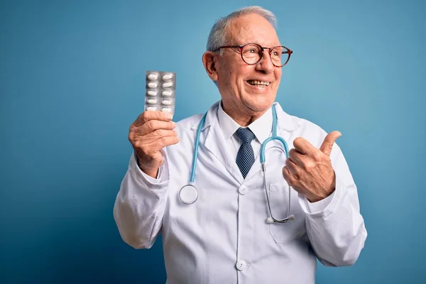 Kıdemli Gri Saçlı Doktor Elinde Ilaç Haplarıyla Mavi Arkaplanı Işaret — Stok fotoğraf