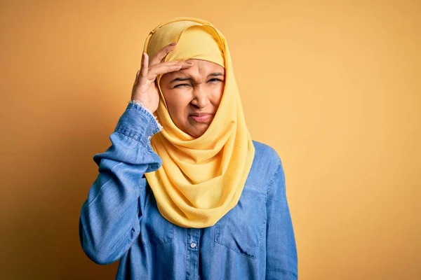年轻美丽的女人 头戴阿拉伯式传统头巾 头戴黄色背景 忧心忡忡 手握额头 神经紧张 急着要发生危机 — 图库照片