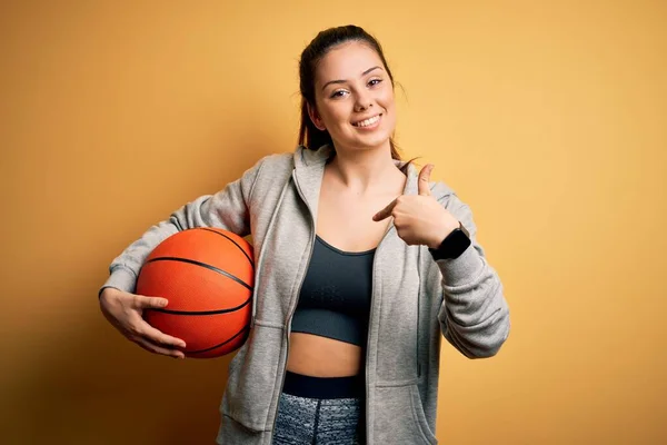 Mladá Krásná Brunetka Sportovkyně Drží Basketbal Přes Žluté Pozadí Překvapivou — Stock fotografie