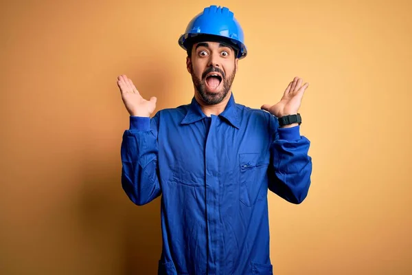 Mechaniker Mit Bart Blauer Uniform Und Schutzhelm Vor Gelbem Hintergrund — Stockfoto