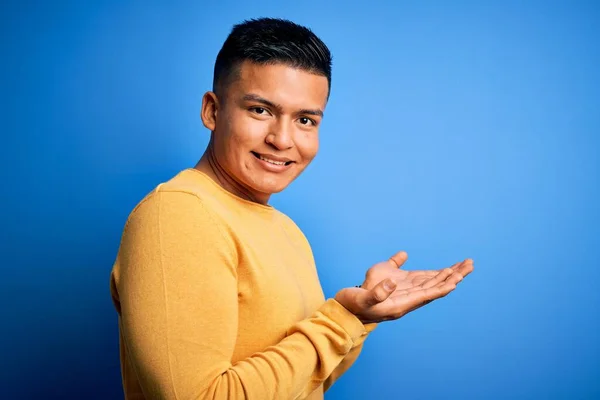 Молодой Красивый Латиноамериканец Желтом Свитере Изолированном Синем Фоне Указывает Сторону — стоковое фото