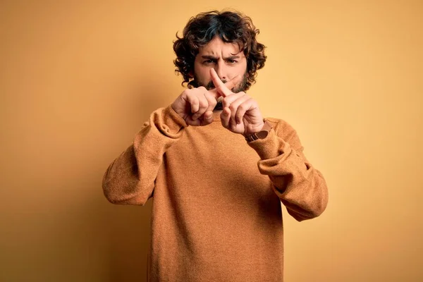 年轻英俊的男人 留着胡子 身穿休闲衫 站在黄色的背景上 拒绝用手指做阴性手势 — 图库照片