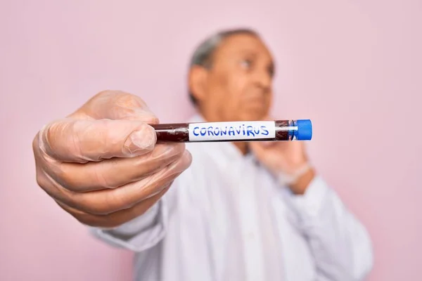 シニアハンサムな角質男保持Coronavirusチューブテスト上の隔離されたピンクの背景深刻な顔考える上に質問 非常に混乱したアイデア — ストック写真
