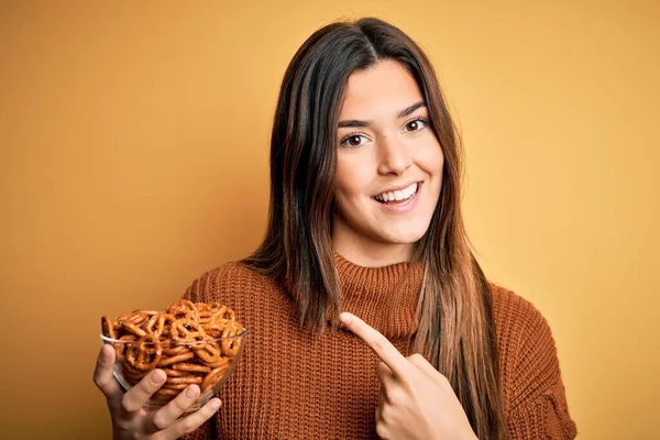 Young Beautiful Girl Eating Baked German Pretzel Standing Isolated Yellow — Stock Photo, Image