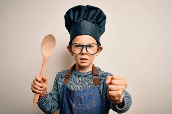 穿着厨师制服 戴着帽子 用木勺做饭的年轻的高加索小厨师孩子 生气得大叫 气疯了 高喊着 怒气冲冲 — 图库照片