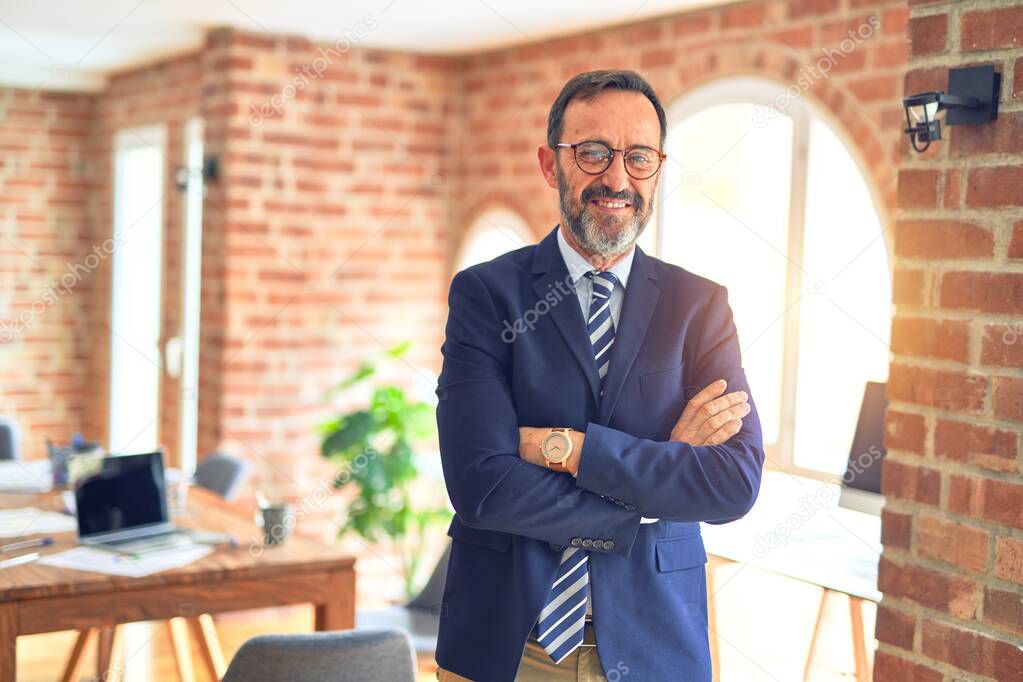 Middle age businessman smiling happy and confident. Standing with smile on face working with businesswoman partner at the office