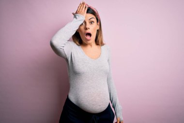 Genç, güzel, esmer bir kadın hamile, pembe arka planda bebek bekliyor. Hatayla el ele tutuşup şaşırmış. Hatayı hatırla. Unuttum, kötü hafıza konsepti.