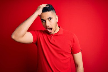 İzole edilmiş arka planda kırmızı polo giyen yakışıklı genç adam hata sonucu el ele verip şaşırdı. Hatayı hatırla. Unuttum, kötü hafıza konsepti.