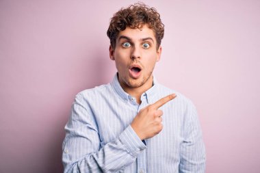 Sarışın, kıvırcık saçlı, beyaz arkaplanlı çizgili tişörtlü, genç ve yakışıklı bir adam..