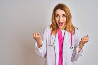 Pembe steteskop takan kızıl saçlı doktor kadın kollarını kaldırarak ve açık gözlerle başarıyı kutluyor. Kazanan konsept.