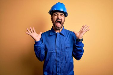 Sarı arka planda mavi üniforma ve güvenlik kaskı takan sakallı tamirci. Kolları havada ve gözleri kapalı heyecanla haykırarak başarıyı kutluyor. Kazanan konsept