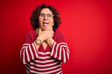 Orta yaşlı güzel kıvırcık saçlı kadın kırmızı arka planda sıradan çizgili süveter giyiyor ve boğularak ölüyor. Sağlık problemi. Boğulma ve intihar konsepti.