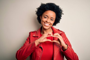 Kıvırcık saçlı, sıradan kırmızı ceketli, aşık bir şekilde gülümseyen, elleriyle kalp sembolü yapan güzel Afro-Amerikan kadın. Romantik konsept.