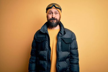 Sakallı, kar maskeli, kar maskeli, kar maskeli ve komik yüzlü yakışıklı kayakçı. Havayla şişmiş ağız, çılgın bir ifade..