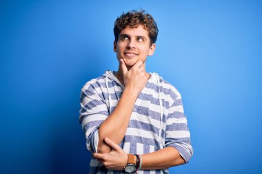 Sarışın, kıvırcık saçlı, sıradan çizgili kazak giyen, eli çenesinde soru soran, düşünceli bir adam. Düşünceli bir yüzle gülümsüyor. Şüphe kavramı.