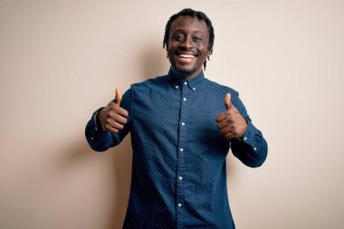 Beyaz arka plan başarısı tabelasının üzerinde dikilmiş, gülümseyen ve mutlu genç ve yakışıklı Afro-Amerikalı bir adam. Neşeli ifade ve kazanan jest.