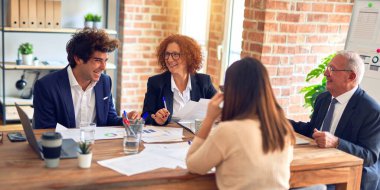 Bir grup iş adamı mutlu ve kendinden emin gülümsüyor. Ofiste birlikte çalışırken gülümseyerek konuşmak..