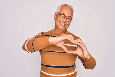 Orta yaşlı, gri saçlı, gözlüklü yakışıklı ve sıradan çizgili süveter giyen, aşkla gülümseyen, elleriyle kalp sembolü yapan bir adam. Romantik konsept.