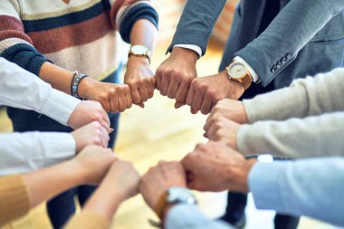 Bir grup işçi ofiste yumruk tokuşturuyor.