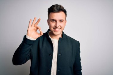 Zarif bir kışlık ceket giyen genç yakışıklı iş adamları izole edilmiş arka planda durup gülümsüyor ve el ve parmaklarıyla 