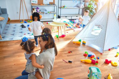 Güzel öğretmen ve bir grup çocuk anaokulunda bir sürü oyuncakla oynuyorlar.