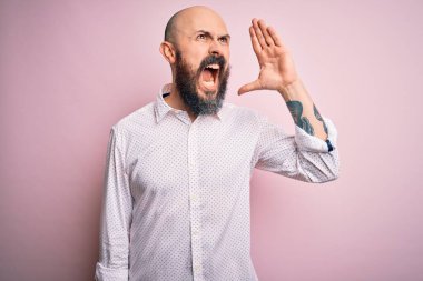 Sakallı, zarif tişörtlü, pembe arka planda yakışıklı bir adam. Avazın çıktığı kadar bağırıyor, avazın çıktığı kadar bağırıyor. İletişim konsepti.