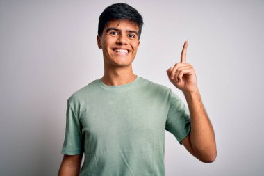 Sıradan tişörtler giyen genç yakışıklı adam izole edilmiş beyaz arka planda durup başarılı bir fikir işaret ediyor. Heyecanlı ve mutlu. Bir numara..