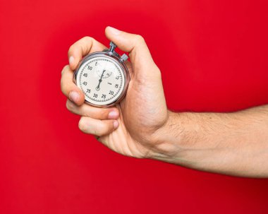 Kronometreyi tutan adamın güzel eli izole edilmiş kırmızı arkaplanda geri sayım yapıyor.