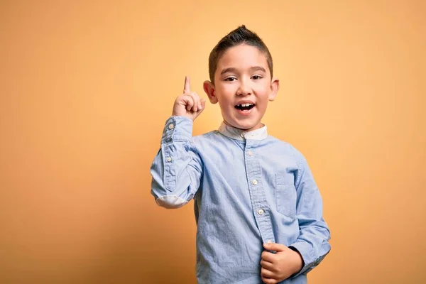 黄色の隔離された背景の上に立つエレガントなシャツを着ている若い男の子は 成功したアイデアで指を指しています 興奮し 第一番 — ストック写真