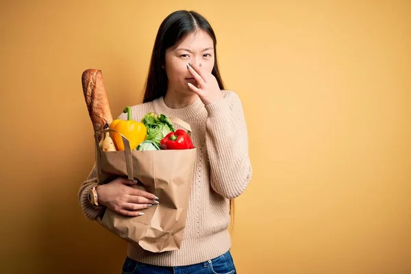 Mladá Asiatka Držící Papírový Sáček Čerstvými Zdravými Potravinami Nad Žlutým — Stock fotografie