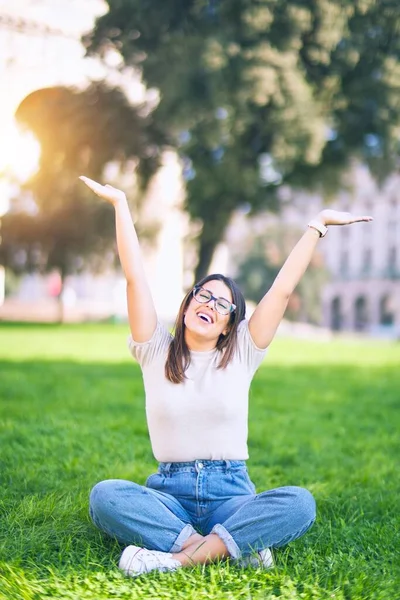若い美しい女性が幸せと自信を笑顔 公園で笑顔で草の上に座って — ストック写真