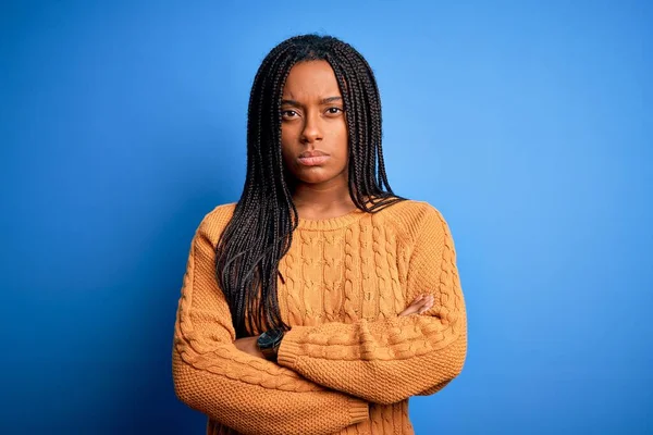 青い隔離された背景の懐疑的で神経の上に立っているカジュアルな黄色のセーターを着ている若いアフリカ系アメリカ人の女性は 両腕を組んで顔に不承認の表現 負の人 — ストック写真