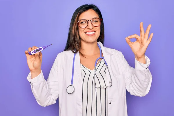 紫色の背景の上に医療用温度計を示すプロの医師の女性は指でOkサインを行う 優れたシンボル — ストック写真