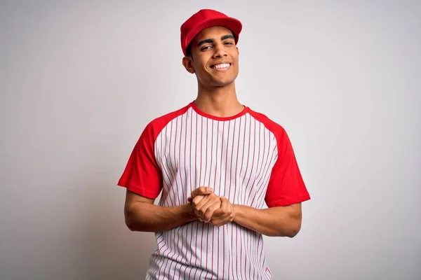 縞模様の野球Tシャツとキャップを手で一緒に身に着けている若いハンサムなアフリカ系アメリカ人のスポーツマンは 指がリラックスして陽気に笑って交差した 成功と楽観的 — ストック写真