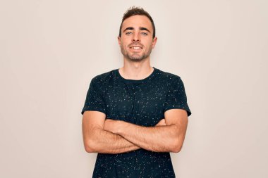 Mavi gözlü, sıradan tişörtlü, beyaz arka planda duran, kollarını kavuşturup kameraya gülümseyen genç yakışıklı bir adam. Pozitif kişi.