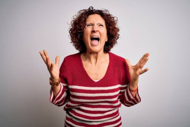 Orta yaşlı güzel kıvırcık saçlı kadın beyaz arka plan üzerine sıradan çizgili süveter giyiyor deli deli deli bağırıyor ve agresif bir ifade ve kollarla bağırıyor. Hayal kırıklığı konsepti.