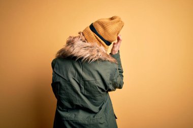 Orta yaşlı güzel sarışın kayakçı kadın kar sporu giysisi ve kayak gözlüğü takıyor geriye doğru, elleri kafasında şüpheyi düşünüyor.