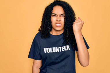 Genç Afro-Amerikalı kıvırcık kadın gönüllü olarak gönüllü olarak gönüllü tişört giyiyor sinirlenmiş ve sinirlenmiş bir şekilde bağırıyor, çıldırmış ve el kaldırarak bağırıyor.
