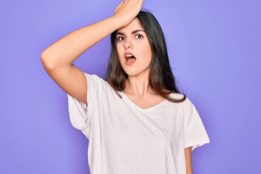 Mor arkaplan üzerine sıradan beyaz tişörtler giyen genç, güzel esmer kadın hata için el ele tutuşarak şaşırdı. Hatayı hatırla. Unuttum, kötü hafıza konsepti.