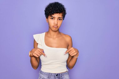 Genç, güzel, Afro-Amerikan bir kadın. Mor arka planda sıradan bir tişört giyiyor. Üzgün ve üzgün görünüyor..