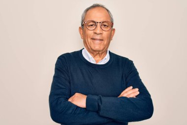 Üst düzey, gri saçlı, süveter giyen ve gözlüklü, izole edilmiş beyaz arka planda mutlu, kollarını kavuşturup kameraya bakan bir adam. Pozitif kişi.