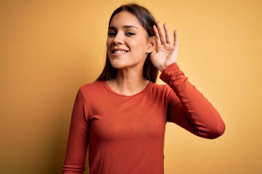 Genç, güzel, esmer bir kadın sarı arka plan üzerinde dikilmiş dedikodu ve dedikodulara kulak misafiri olurken gülümsüyor. Sağırlık kavramı.