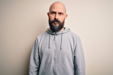 Yüzünde ciddi bir ifadeyle pembe arka planda duran sakallı yakışıklı, kel bir adam. Basit ve doğal bir şekilde kameraya bakıyorsun..