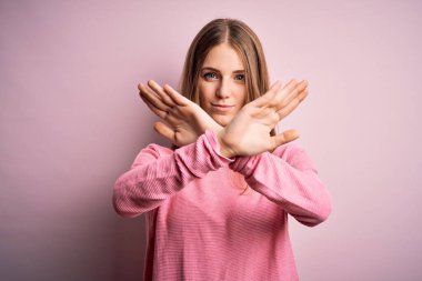 Genç, güzel, kızıl saçlı bir kadın pembe arka planda günlük süveter giyiyor. Reddedilmiş yüz ifadesi, kollar ve avuç içleri ters dönmüş, kızgın yüz ifadesi takınıyor.