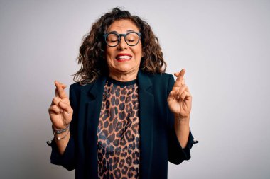 Orta yaşlı esmer iş kadını gözlüklü, izole edilmiş beyaz arka planda duran umut ve gözler kapalı gülümseyerek el kol hareketi yapan bir kadın. Şans ve batıl inanç..