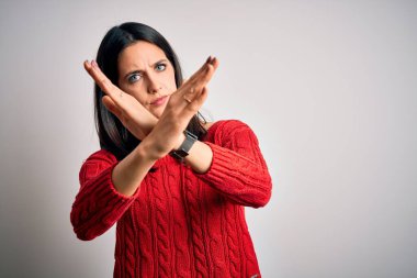 Mavi gözlü genç esmer kadın izole edilmiş beyaz arka planda günlük süveter giyiyor. Kollarını kavuşturup, avuçlarını açarak negatif işaret veriyor. Kızgın surat.
