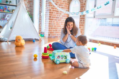 Güzel öğretmen ve bebek anaokulunda bir sürü oyuncakla oynuyorlar.