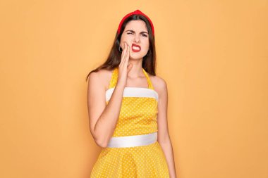 50 'li yılların modasına uygun elbiseler giyen genç ve güzel bir kadın diş ağrısı ya da diş ağrısı yüzünden ağız ve acı dolu bir ifadeyle birbirine dokunuyor. Dişçi