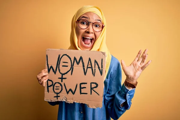 ムスリムのヒジャーブを身に着けている巻き毛の美しい女性は 女性の権利を求めるバナーを保持非常に幸せと興奮 大きな笑顔で叫んで勝利を祝う勝者式と手を上げ — ストック写真